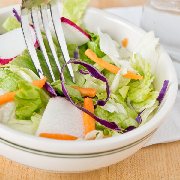 A close-up of a Homer Laughlin green banded nappie bowl filled with a vegetable salad with a fork.