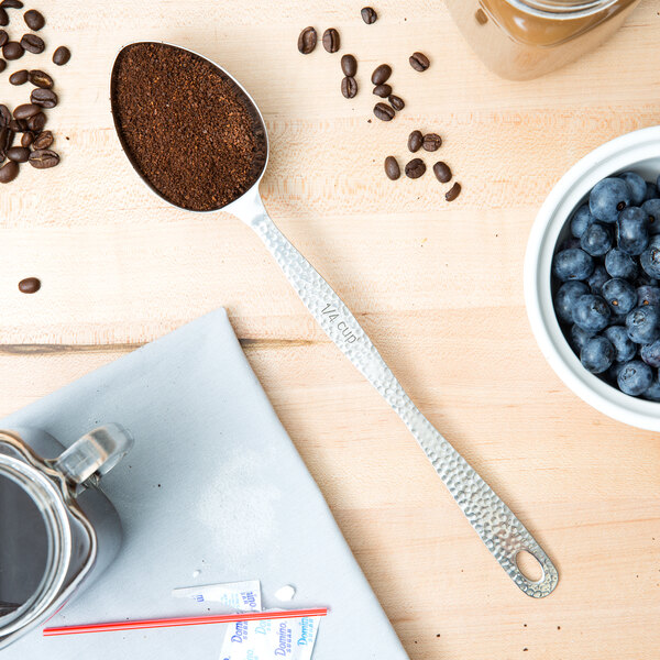 A stainless steel spoon with ground coffee and blueberries.