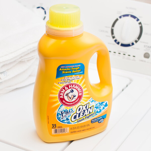A bottle of Arm & Hammer Plus OxiClean Liquid Laundry Detergent on a washing machine.