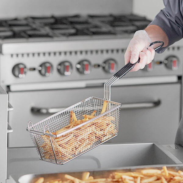 A person holding a R & V Works fryer basket of fries.