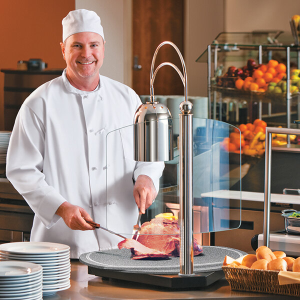 A chef using a Hatco Carving Station to cook meat in a hotel kitchen.