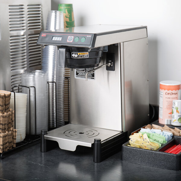 A Bunn SmartWAVE low profile coffee and tea brewer on a counter next to cups.