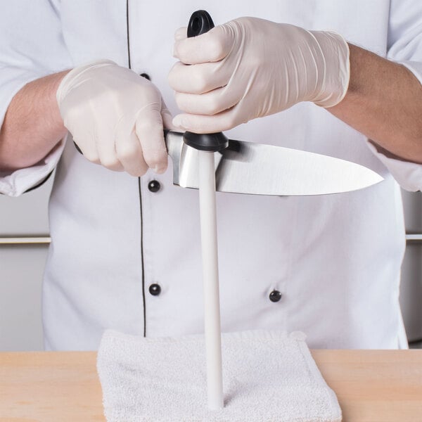A person in a white coat using a Mercer Culinary ceramic knife sharpener.