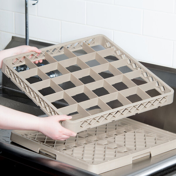 A person holding a Vollrath Traex glass rack extender in a school kitchen.