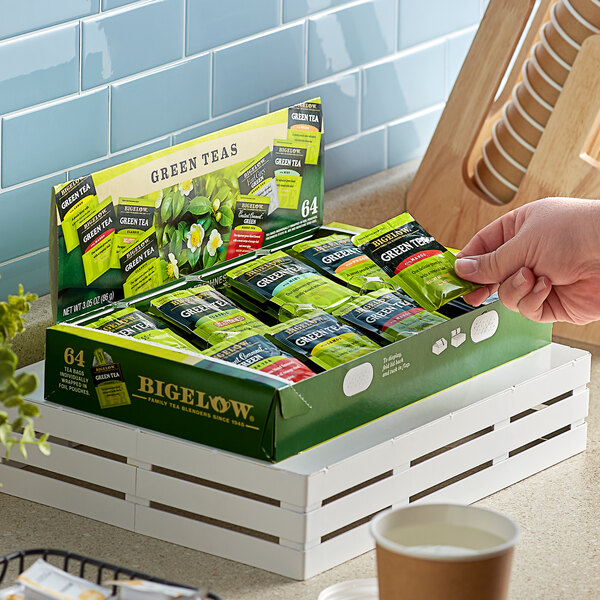 A hand holding a box of Bigelow Green Tea Bag Variety Tray Packs.