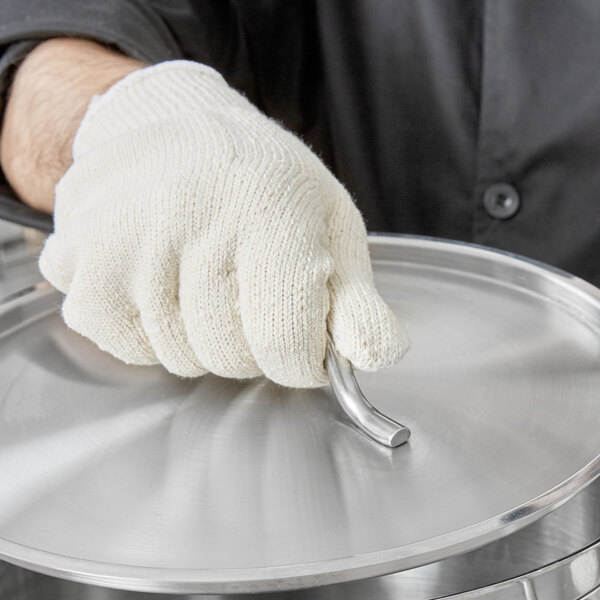 A person wearing a white heat-resistant glove holding a metal object.