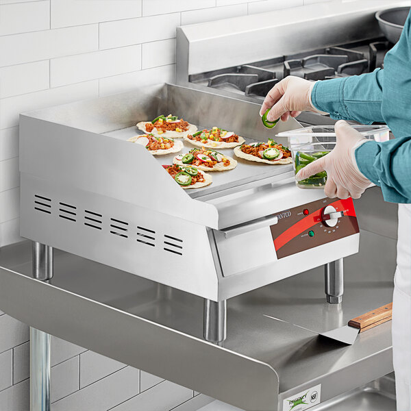 A person using an Avantco electric countertop griddle to cook food.