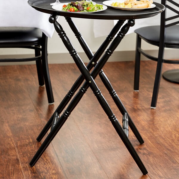 A black Lancaster Table & Seating folding tray stand with a tray of food on it.