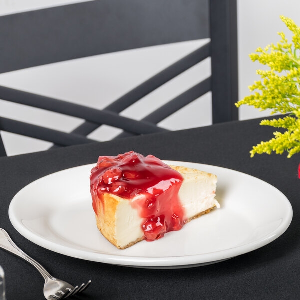 A slice of cheesecake with red sauce on a Homer Laughlin white china platter.