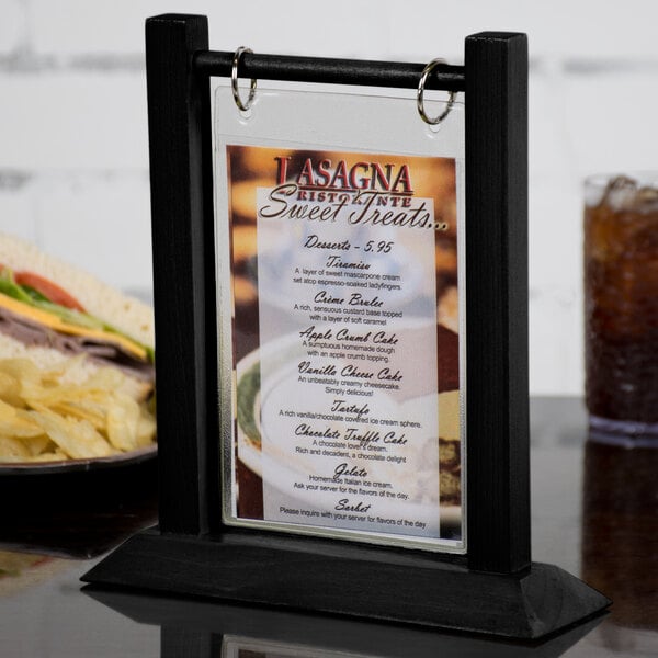 A black wood flip top table tent with a menu inside on a table.