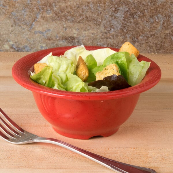 A red bowl of salad with a fork.