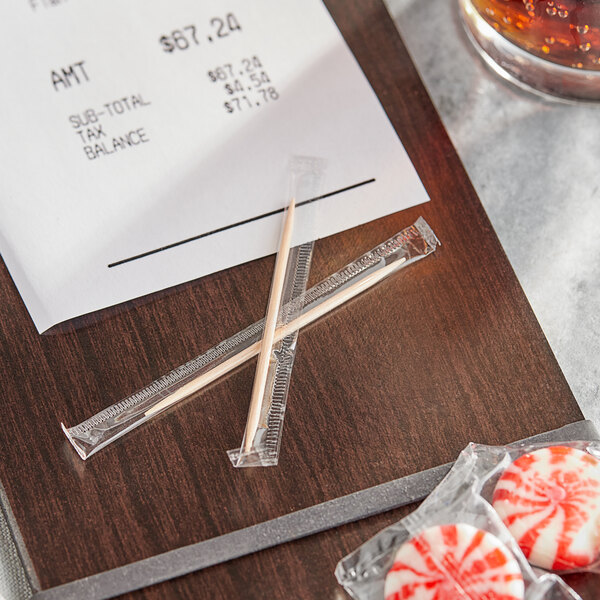 A box of Royal Paper individually wrapped wooden toothpicks on a table with a receipt and candy.