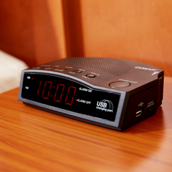 A black Conair digital alarm clock on a table.