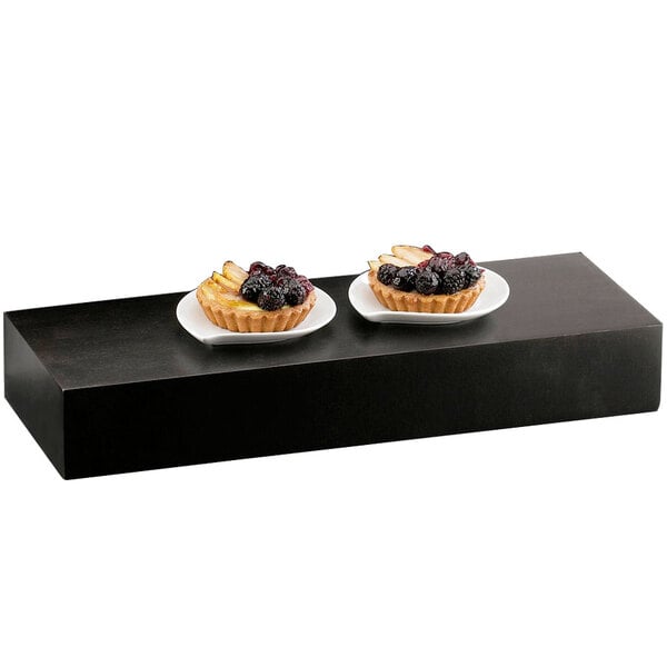 Two plates of fruit tarts on a black Cal-Mil plate riser.