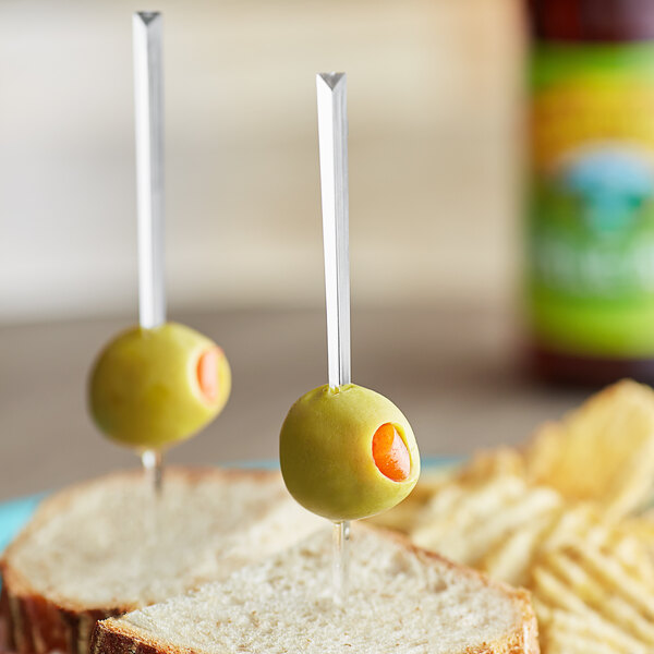 A sandwich on a plate with a Royal Paper clear plastic prism food pick in a green olive.
