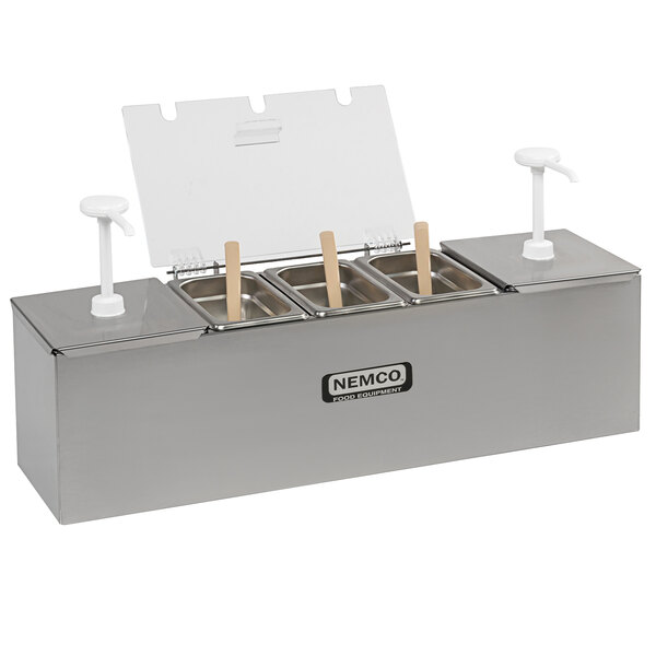 A stainless steel Nemco condiment bar on a counter with four condiment containers.