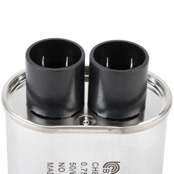 A close-up of a Solwave high voltage capacitor with two black metal caps.