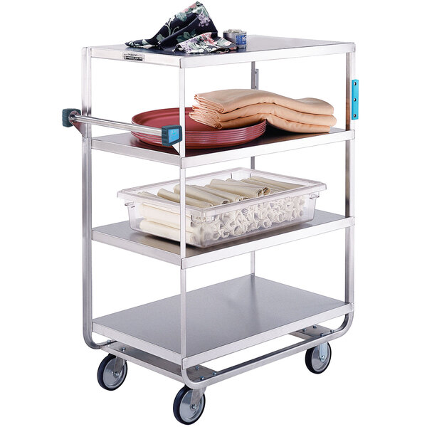 A Lakeside stainless steel six shelf utility cart with trays of food and towels.