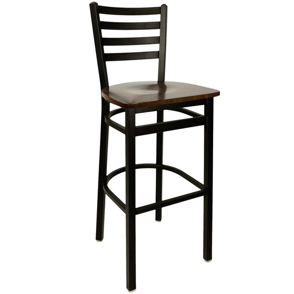 A BFM Seating black metal ladder back barstool with a walnut wooden seat.