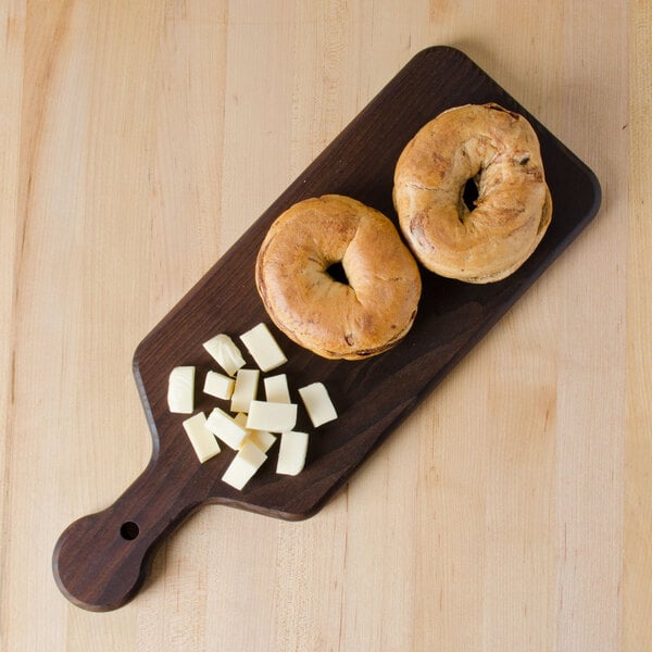 An American Metalcraft ash wood serving board with two bagels and cheese on it.