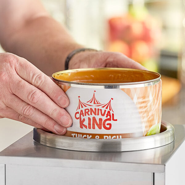 A person holding a Carnival King #10 can of caramel dip.
