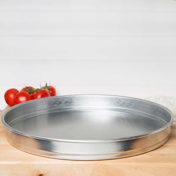 An American Metalcraft aluminum cake pan on a wooden surface with tomatoes.