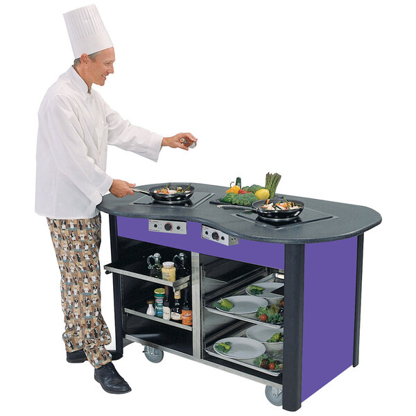 A chef cooking food in a pan on a Lakeside stainless steel cooking cart.