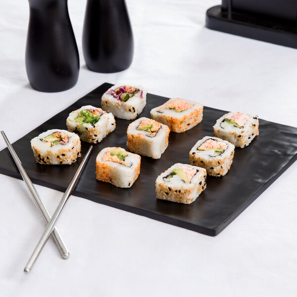 An American Metalcraft black faux slate melamine platter with sushi and chopsticks on a table.