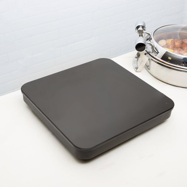 A black square Vollrath countertop induction warmer on a white surface.