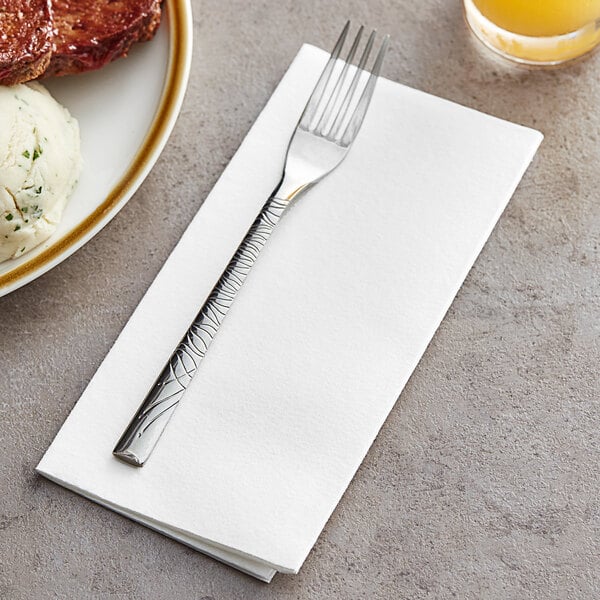 A Touchstone by Choice white linen-feel dinner napkin with a fork on it next to a plate of food.
