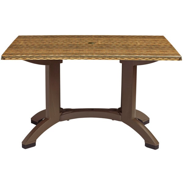 A Grosfillex rectangular table with a wicker top and brown pedestal base.