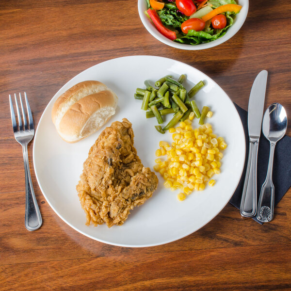 A CAC Majesty bone china coupe plate with chicken, corn, and green beans on it with a fork.