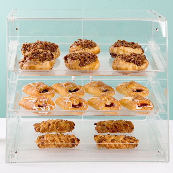 A Cal-Mil three tier U-build pastry display case filled with pastries on a counter.