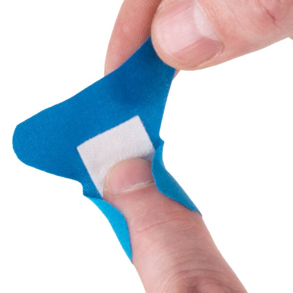 A person putting a blue woven adhesive fingertip bandage on their finger.