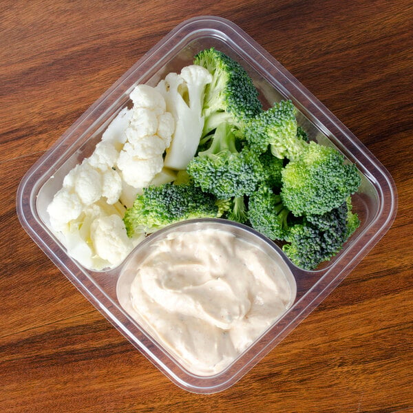 A Fabri-Kal clear plastic deli container with broccoli and cauliflower.