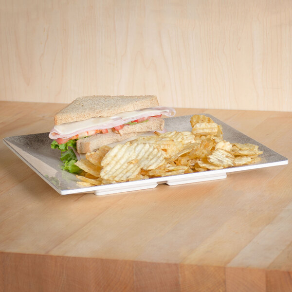 A sandwich with meat and vegetables and chips on a Thunder Group Jazz melamine plate.