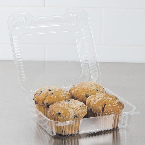 A Dart clear hinged plastic container filled with muffins.