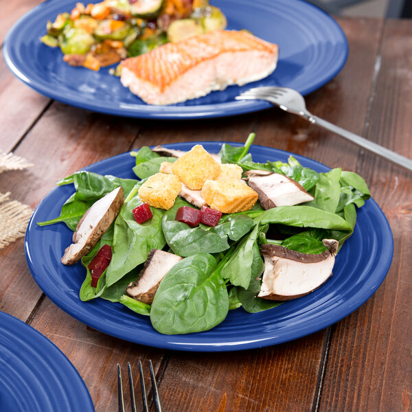 A Fiesta® luncheon plate with salad and fish on a table with a fork.
