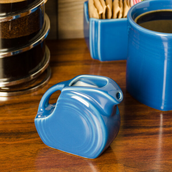 A blue ceramic pitcher on a wood surface.