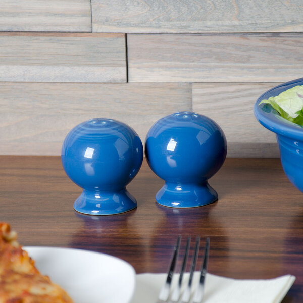 Two blue Fiesta salt and pepper shakers on a table.
