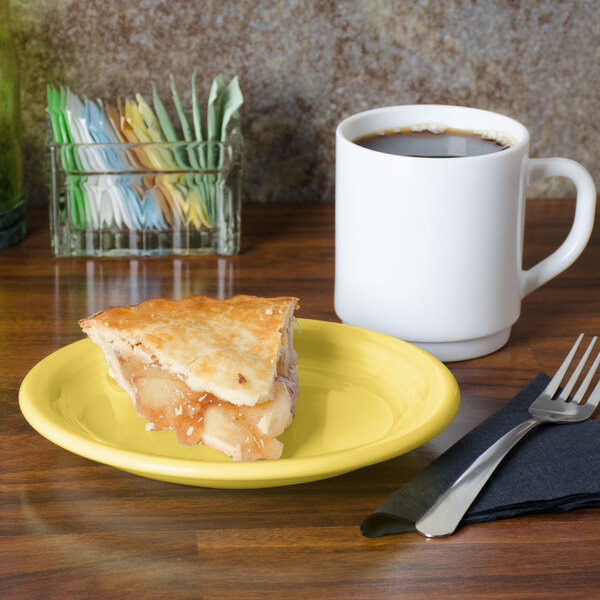 A slice of pie on a Fiesta® sunflower yellow plate next to a white mug of coffee.
