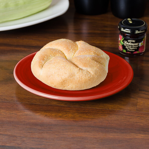 A Fiesta® Scarlet bread and butter plate with a roll on it.