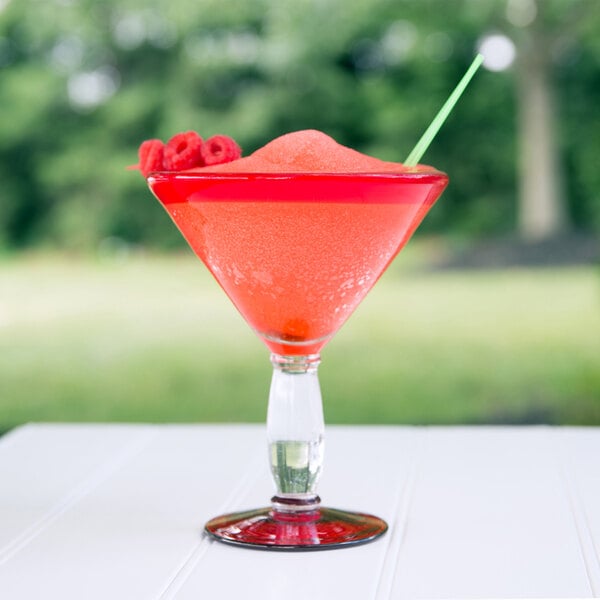 A close up of a Libbey martini glass with a red drink and a green garnish.