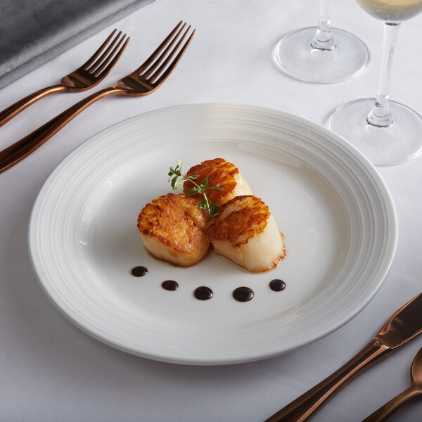 A Tuxton Pacifica bright white china plate with scallops and a fork on it.