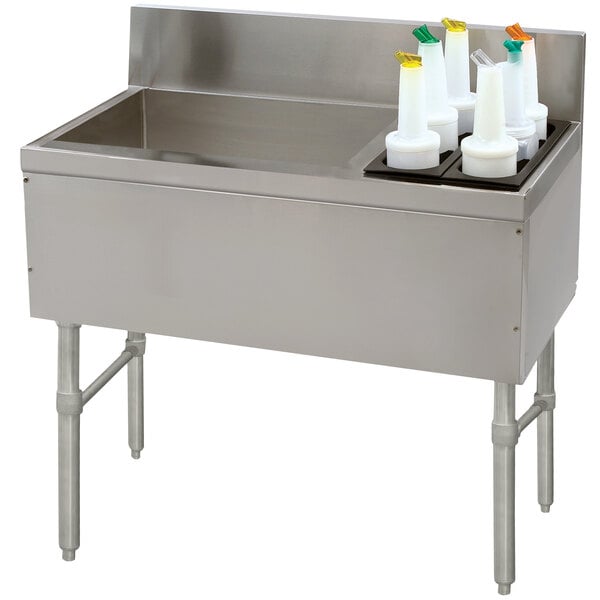A stainless steel Advance Tabco ice bin and bottle storage combo unit on a counter with containers.