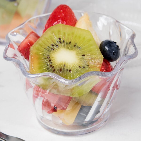 A clear plastic Cambro swirl bowl filled with sliced fruit.