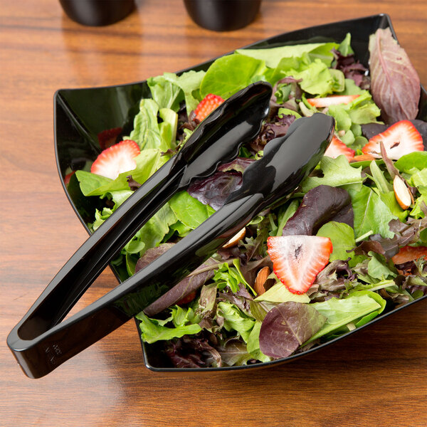 A salad with strawberries in a bowl with Fineline black plastic tongs.