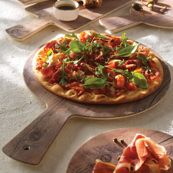 An Elite Global Solutions faux driftwood serving board with pizza, meat, and vegetables on it.