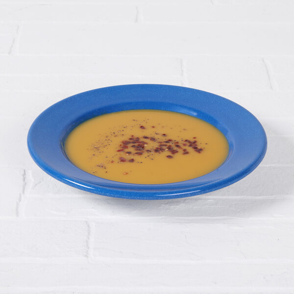 A blue speckled bowl of soup on a white table.