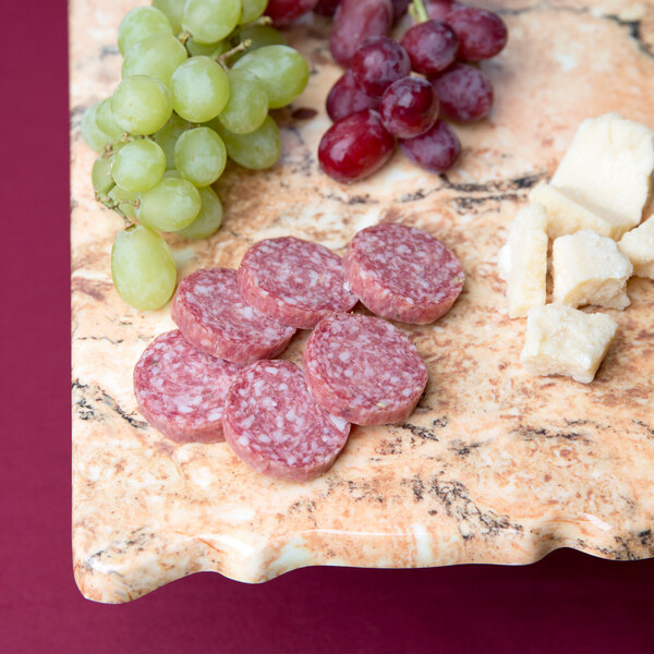 A rectangular Elite Global Solutions rustic granite platter with cheese and grapes on a table.